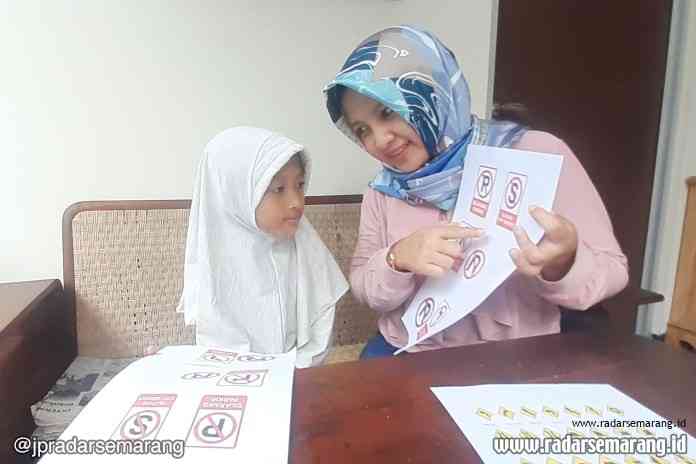 Indah Fajarwati, 38, saat mengenalkan pentingnya rambu-rambu lalu lintas kepada anak pertamanya, Al Kayla Mafira Ariawan, 8. (Alvi Nur Janah / Jawa Pos Radar Semarang)