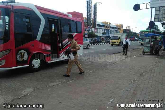 Seorang penumpang yang mengenakan seragam ASN asal Salatiga tetap menggunakan transportasi umum bus jurusan Semarang-Solo yang kosong di terminal bayangan Banyumanik depan Swalayan ADA Setiabudi, Senin (15/6/2020). (Miftahul A’la/Jawa Pos Radar Semarang)