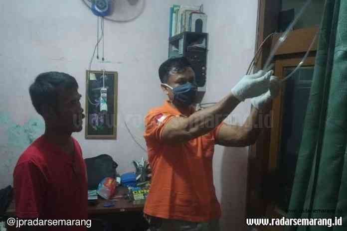 Petugas kepolisian menunjukkan selang yang digunakan korban untuk mengakhiri hidupnya di dalam kamar. (M Hariyanto/Jawa Pos Radar Semarang)