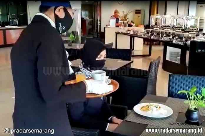 Karyawan Hotel Sahid Mandarin Hotel menggunakan face shield dan berkaus tangan saat melayani makan tamu di resto Rabu (15/7/2020). (Lutfi Hanafi/Jawa Pos Radar Semarang)
