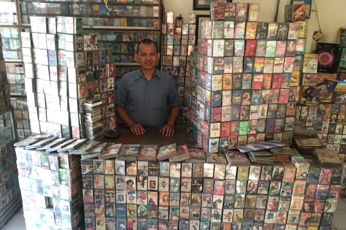 Deny saat berpose di antara kaset-kaset pita yang ada di RM Padang miliknya yang berada di deretan ruko sekitaran bundaran Bubakan. (Eko Wahyu Budiyanto/Jawa Pos Radar Semarang)