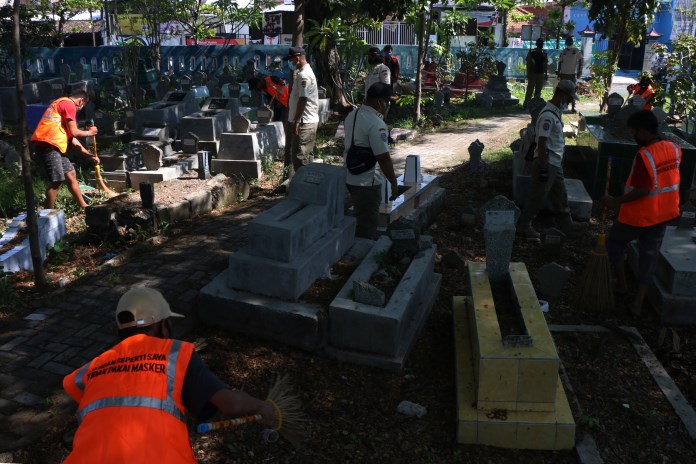 Sebanyak 15 warga yang terjaring razia protokol kesehatan mendapat sanksi sosial menyapu di kompleks tempat pemakaman umum (TPU) Soponyono, Semarang Utara (30/9/2020). (Nur Chamim/Jawa Pos Radar Semarang)