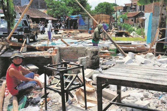Warga sedang membongkar kiosnya secara mandiri. Alat berat mulai bekerja memulai pembangunan talud di tepi Sungai Tuntang Lama. (Wahib pribadi/Jawa Pos Radar Semarang)