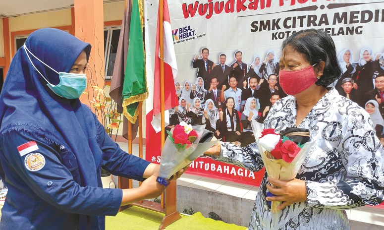 Siswa SMK Citra Medika Kota Magelang memberikan kado bunga kepada guru tertua di atas panggung peringatan Hari Guru Nasional kemarin (25/11/2020). (Puput Puspitasari/Jawa Pos Radar Semarang)