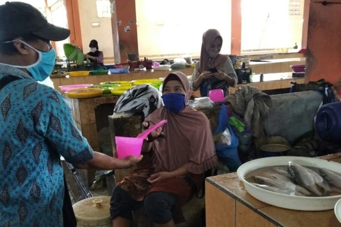 Pedagang Pasar Bintoro menggunakan gayung sebagai alat bertransaksi dengan pembeli. Gayung untuk jaga jarak. (Wahib Pribadi/Jawa Pos Radar Semarang)