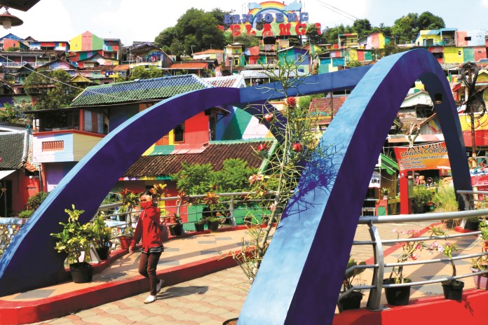 Seorang pengunjung yang memakai masker melintas di kawasan Kampung Pelangi Kota Semarang. Pemprov Jateng akan memperketat pengawasan di destinasi wisata selama masa liburan akhir tahun 2020. (Dok Nurchamim/Jawa Pos Radar Semarang)