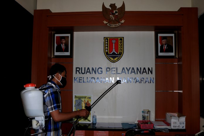 Seorang relawan melakukan penyemprotan cairan disinfektan di Kantor Kelurahan Manyaran, Semarang Barat (2/11/2020). (Nurchamim/Jawa Pos Radar Semarang)
