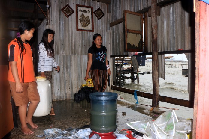 Warga RT 01/RW 15 Kelurahan Tanjung Mas menyelamatkan perabotan rumah karena tersapu gelombang besar. (Nurchamim/Jawa Pos Radar Semarang)