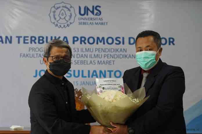 Joko Sulianto saat menerima cinderamata dari Dr Muhdi setelah dinobatkan sebagai doktor UNS. (Istimewa)