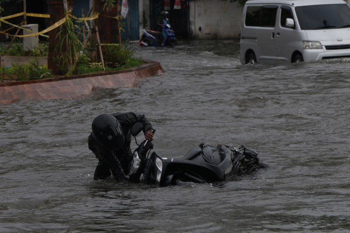 Seorang pengendara motor terjatuh saat menerjang banjir di bundaran Bubakan, Semarang Timur. (NURCHAMIM/JAWA POS RADAR SEMARANG)