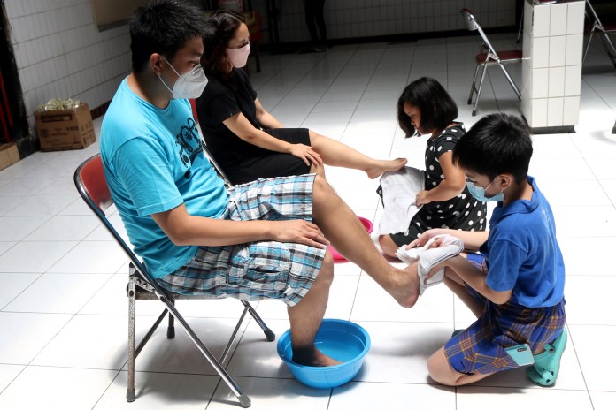 Anak membasuh kaki orang tua saat tradisi Bakti Basuh Kaki yang digelar di Gedung Rasa Dharma, Gang Pinggir, kawasan Pecinan, Semarang, Kamis (11/2/2021). (NURCHAMIM/JAWA POS RADAR SEMARANG)