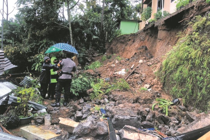 Kapolsek Watumalang meninjau langsung lokasi longsor di belakang Kecamatan Watumalang untuk strerilisasi tempat. (Istimewa)