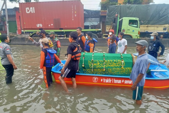 Warga, dibantu petugas BPBD, TNI/Polri mendorong dan menarik perahu yang di atasnya ada keranda berisi jenazah Sukarjo. (Istimewa)