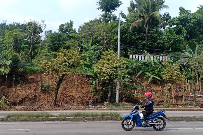 Tebing di TPU Tikung, Wonosari, Ngaliyan, longsor hingga menyebabkan dua makam ikut tergerus. (ADENNYAR WYCAKSONO/JAWA POS RADAR SEMARANG)