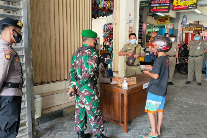 Warga sedang melakukan pendataan diri akibat melanggar protokol kesehatan dengan tidak memakai masker. (Istimewa)