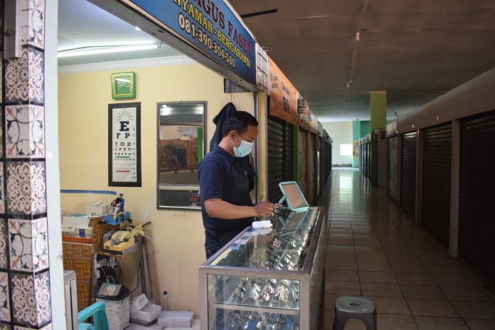 Arfian, pemilik optik menunggu pembeli sambal membersihkan kacamata di kios Lantai 3 Pasar Bulu, Semarang, Selasa (23/2/2021). (TITIS ANIS FAUZIYAH/JAWA POS RADAR SEMARANG)