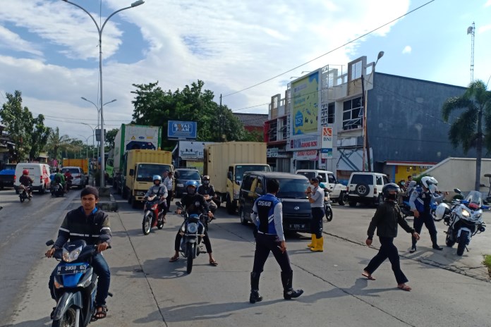 Petugas Dishub Kota Semarang mengatur kendaraan yang ingin putar balik untuk menghindari kemacetan di Jalan Wolter Monginsidi, Semarang. (ADENNYAR WYCAKSONO/JAWA POS RADAR SEMARANG)