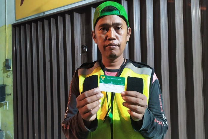 Agus Siswanto menunjukkan kartu JKN-KIS yang dibawa saat kerja sif malam, menjaga parkir di salah satu rumah makan di Kota Magelang. (Istimewa)