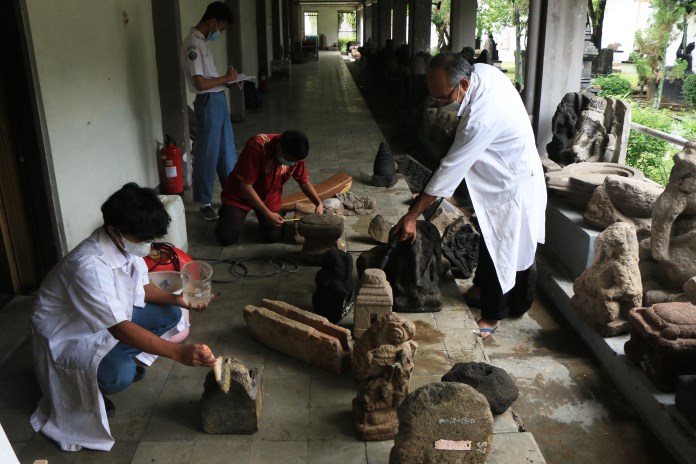 Petugas konservasi Museum Ranggawarsita Kota Semarang sedang membersihkan koleksi arca agar bersih dari jamur, debu dan lumut. (NUR CHAMIM/JAWA POS RADAR SEMARANG)
