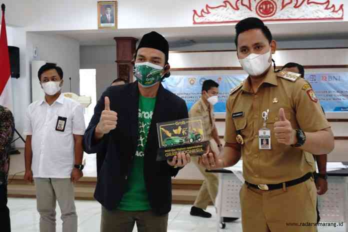 City Manager Jateng Grab, Ramdhan Fitriadi  dan Senior Manager Government Relation Gojek Jateng-DIY, Saiful Bakhtiar saat memberikan cinderamata kepada Bupati Kendal, Dico M Ganinduto. (BUDI SETIYAWAN/JAWA POS RADAR SEMARANG)