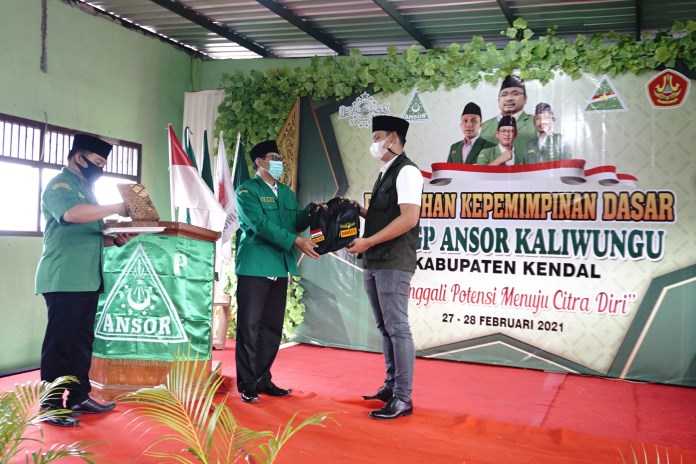 Ketua PAC GP Ansor Kendal memberikan jaket Banser kepada Bupati Kendal Dico Mahtado Ganinduto dalam kegiatan PKD di SMK NU 03 Kaliwungu kemarin (28/2/2021). (BUDI SETIYAWAN/JAWA POS RADAR SEMARANG)