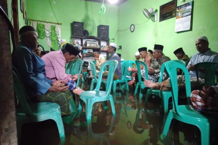 Warga tetap menggelar tahlilan meski banjir menggenang di Dukuh Bugangan, Rabu (3/3/2021) malam lalu. (Ananta Erlangga Musa / JAWA POS RADAR SEMARANG)