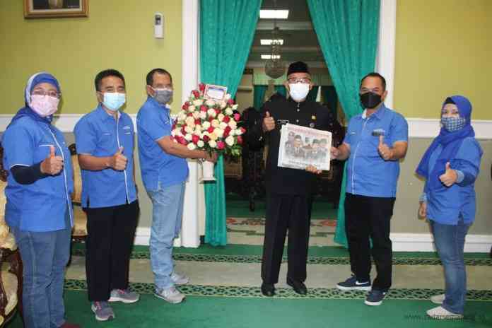 Direktur Jawa Pos Radar Semarang Baehaqi menyerahkan buket bunga tanda cinta kepada Bupati Demak HM Natsir. (WAHIB PRIBADI/JAWA POS RADAR SEMARANG)