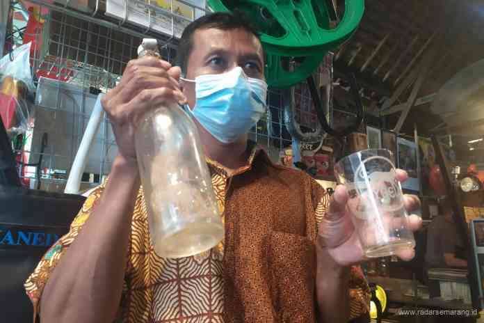 SUDAH TAK BEROPERASI: Bekas pabrik air minum dalam kemasan pertama di Kota Semarang. (kanan) Salah satu penjual barang antik di belakang Gereja Blenduk Kota Lama menunjukkan bekas botol Hygeia. ( EKO WAHYU BUDIYANTO/JAWA POS RADAR SEMARANG)