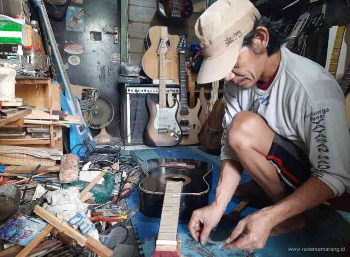 Didi perajin gitar memasang fret gitar saat mengerjakan pesanan di kediamannya, di Jalan Warigalit Raya, Semarang, Jumat (2/4/2021). (TITIS ANIS FAUZIYAH/JAWA POS RADAR SEMARANG)