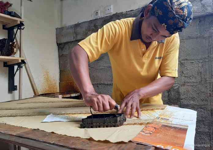 Muridi mengecap lilin ke kain batik di rumah produksi yang menyatu dengan kediamannya. (TITIS ANIS FAUZIYAH/JAWA POS RADAR SEMARANG)