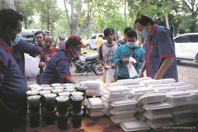 Ketua Yayasan Pancaka, Wong Aman Gautama bersama kru membagikan takjil kepada warga Kelurahan Sambiroto dan Tandang di Krematorium Kedungmundu, kemarin (24/4/2021). (M NUR WAHIDI/JAWA POS RADAR SEMARANG)