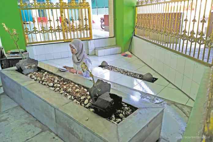 Peziarah sedang melantunkan ayat suci Alquran di Makam Syarifah Fatimah binti Husain Al-Aidrus. (MIFTAHUL A’LA/JAWA POS RADAR SEMARANG)