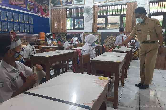 Guru SD Negeri Pekunden menyemprot meja siswa dengan cairan disinfektan usai pembelajaran tatap muka. (TITIS ANIS FAUZIYAH/JAWA POS RADAR SEMARANG)
