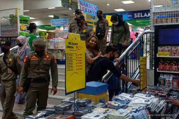 Petugas Satpol PP Kota Semarang meminta pengunjung ADA Siliwangi tetap mengenakan masker, dan tidak berkerumun selama berbelanja. (ADENNYAR WYCAKSONO/JAWA POS RADAR SEMARANG)