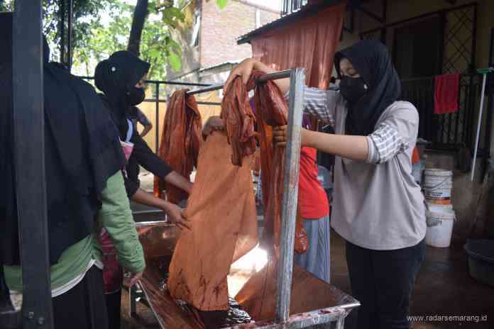 WARNAI BATIK: Peserta pelatihan di Rumah Belajar Batik mencelupkan kain batik buatannya ke dalam pewarna alami. (TITIS ANIS FAUZIYAH/JAWA POS RADAR SEMARANG)