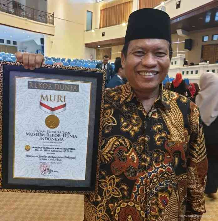 Dr dr Budi Laksono MHSc menunjukkan sertifikat MURI pembuatan jamban berkelanjutan terbanyak. (Istimewa)
