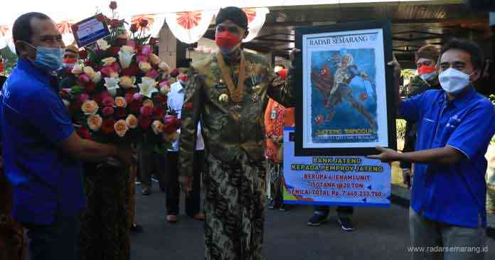 MANGAYUBAGYO HUT JATENG : Direktur Jawa Pos Radar Semarang Baehaqi dan Pemred Arif Riyanto menyerahkan buket bunga dan karikatur Ganjar kepada Gubernur Ganjar Pranowo dalam rangka mangayubagyo HUT Jateng. (NUR CHAMIM/JAWA POS RADAR SEMARANG)