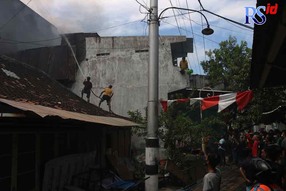 Petugas pemadam kebakaran dan warga berusaha memadamkan api yang membakar tiga toko, Minggu (29/8/2021). (NUR CHAMIM/JAWA POS RADAR SEMARANG)