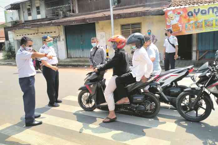 Dishub Provinsi Jawa Tengah dan Kabupaten Pekalongan saat memberi sosialisasi kepada pengendara yang berhenti di zebra cross Simpang Tugu Durian, Karanganyar, Kabupaten Pekalongan Selasa (3/8/2021). (NANANG RENDI AHMAD/JAWA POS RADAR SEMARANG)