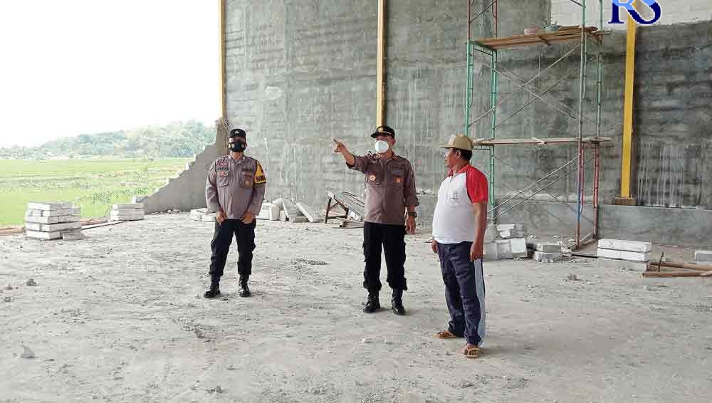 Kapolsek Gringsing Iptu Andi Fajar meninjau dinding GOR yang ambruk dan meminta keterangan Kades Mentosari Suwaji.  (Istimewa)