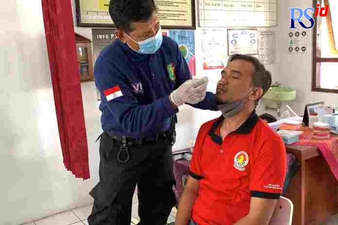 Petugas Dokkes Polres Salatiga sedang mengambil sampel swab antigen salah seorang guru. (Istimewa)