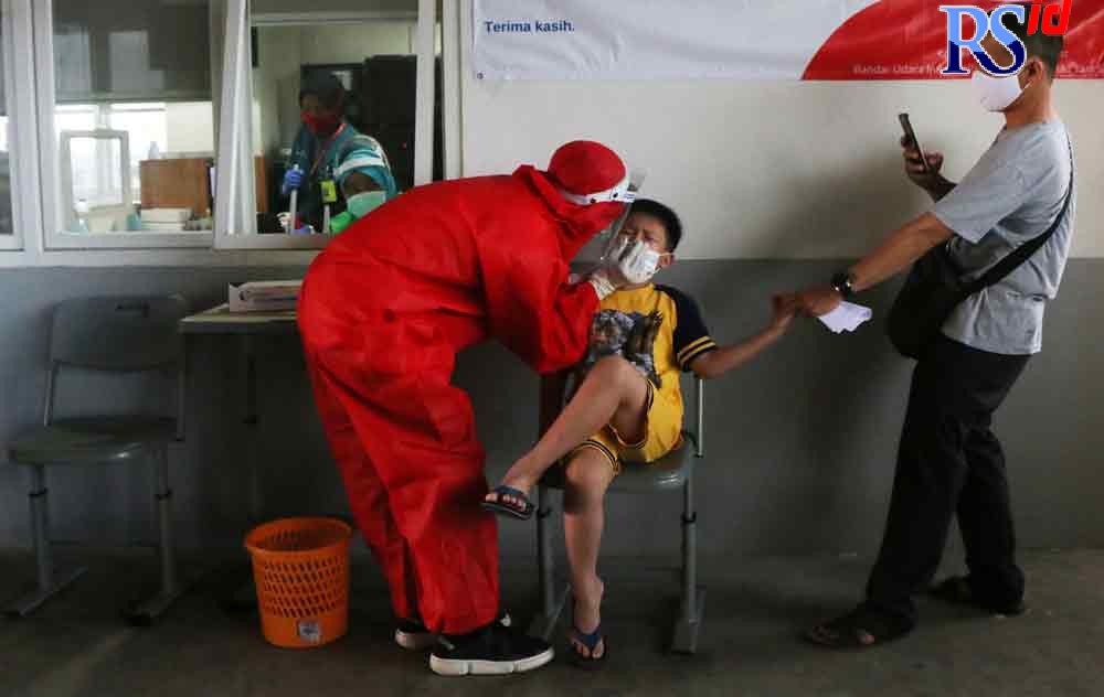 Seorang anak didampingi orang tuanya sedang melakukan tes PCR di bandara. (DOKUMEN NUR CHAMIM/ JAWA POS RADAR SEMARANG)