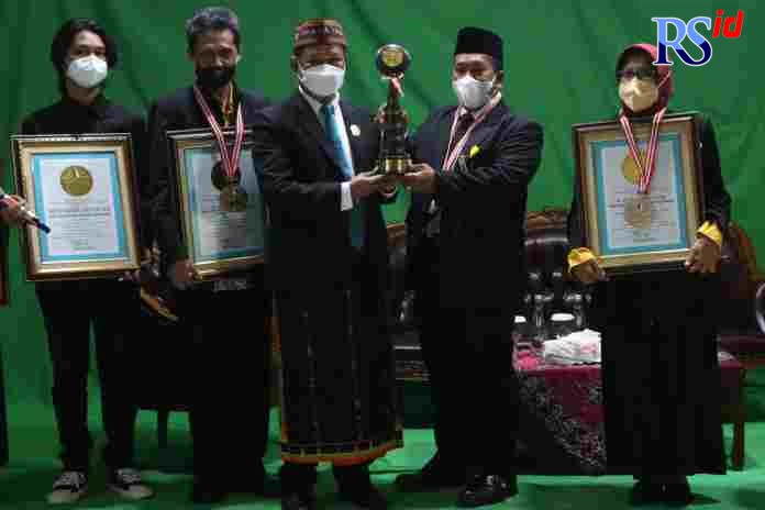 Direktur Leprid Paulus Pangka menyerahkan penghargaan kepada Rektor Unnes Prof Dr Fathur Rokhman di Aula Gedung Fakultas Bahasa dan Seni Unnes Kamis (28/10/2021). (NUR CHAMIM/JAWA POS RADAR SEMARANG)