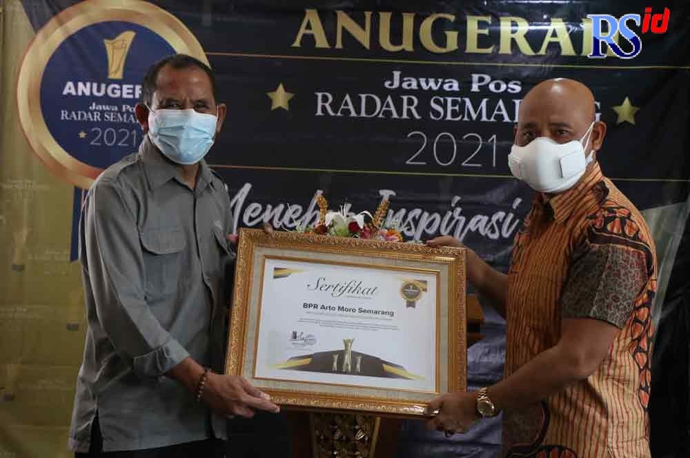 Direktur Jawa Pos Radar Semarang Baehaqi menyerahkan sertifikat penghargaan Anugerah Jawa Pos Radar Semarang 2021 kepada Komisaris Utama sekaligus Pemegang Saham Pengendali BPR Arto Moro Dr H Subyakto SH MH MM. (NURCHAMIM/JAWA POS RADAR SEMARANG)