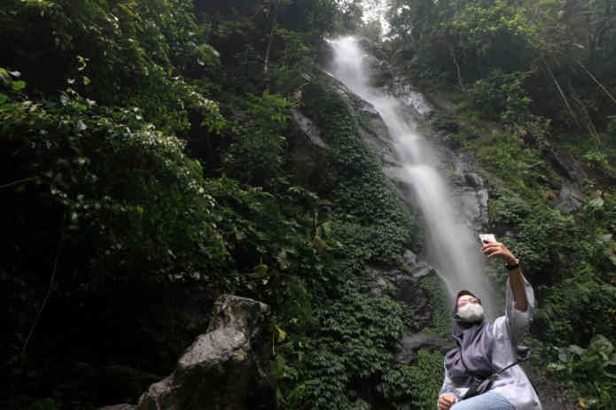 Pengunjung berselfie dibawah Curug Semirang, meski lokasi di alam. Pengunjung tetap mematuhi prokes yang ditetapkan pengelola. (ADITYO DWI/JAWA POS RADAR SEMARANG)