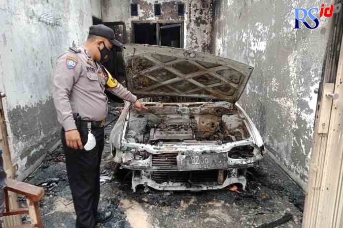 TINGGAL PUING: Seorang petugas melihat kondisi mobil yang sudah tinggal rangka karena terbakar. (Ist)