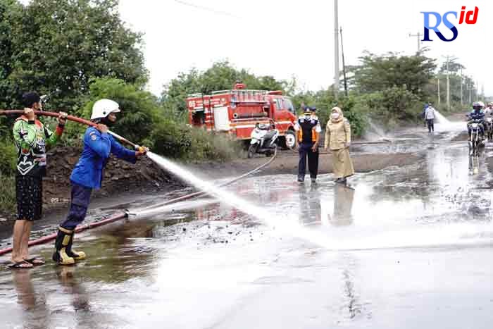 Petugas Dishub Kendal bersama Damkar melakukan penyemprotan material tanah yang menutup Jalan Pelabuhan Kendal, Senin (7/3/2022).  (BUDI SETIYAWAN/JAWA POS RADAR SEMARANG)