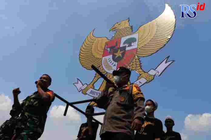Warga RW 15 dan 18, Kelurahan Tlogosari Kulon, bersama anggota TNI-Polri memanggul Garuda Pancasila, sebagai rangkaian pengukuhan Kampung Pancasila, kemarin. (NUR CHAMIM/ JAWA POS RADAR SEMARANG)