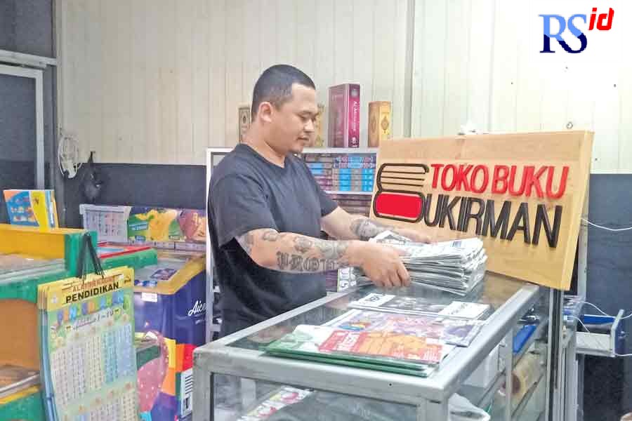 Fernando, generasi ketiga pengelola Toko Sukirman Wonosobo saat merapikan koran di tokonya. (Sigit Rahmanto/Jawa Pos Radar Semarang)