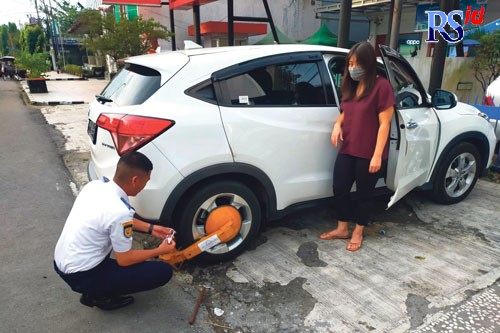 Petugas Dishub Kota Magelang menggembok mobil yang diparkir sembarangan di Jalan Ahmad Yani, Alun-alun Timur Kota Magelang dalam patroli kawasan tertib lalu lintas, Selasa (24/5). (Istimewa)